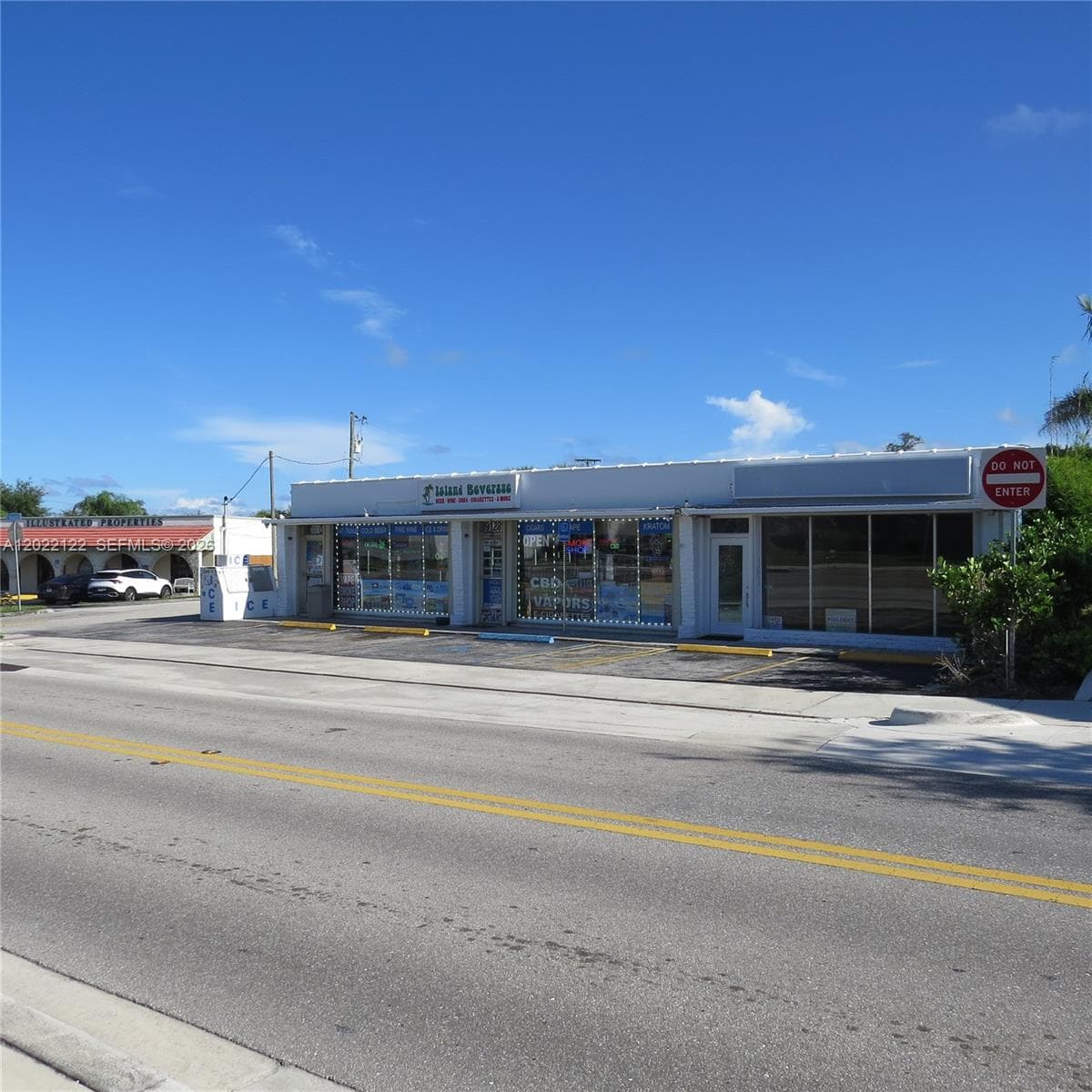 Single-story commercial building featuring extensive storefront glass, paved surface parking, and exterior signage mounting
