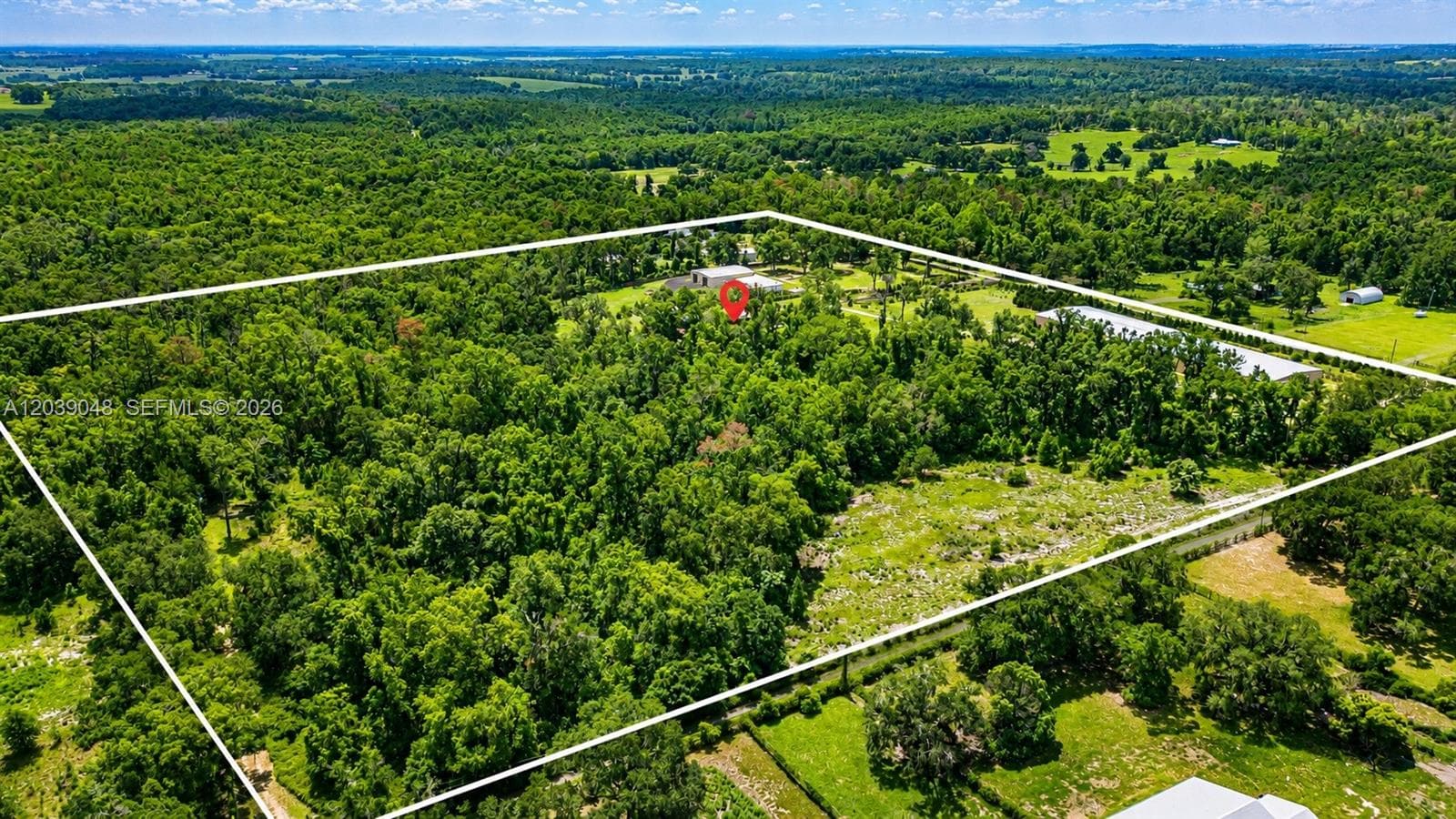 Stunning aerial perspective showcasing over 24 acres of usable land, offering privacy, expansion potential, and multiple structures including the residence and detached garage buildings. A rare opportunity with endless possibilities for residential, agricultural, or investment use.