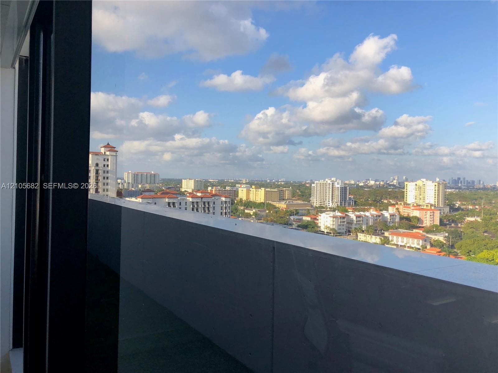 Elevated balcony featuring a glass panel railing and panoramic urban skyline exposure