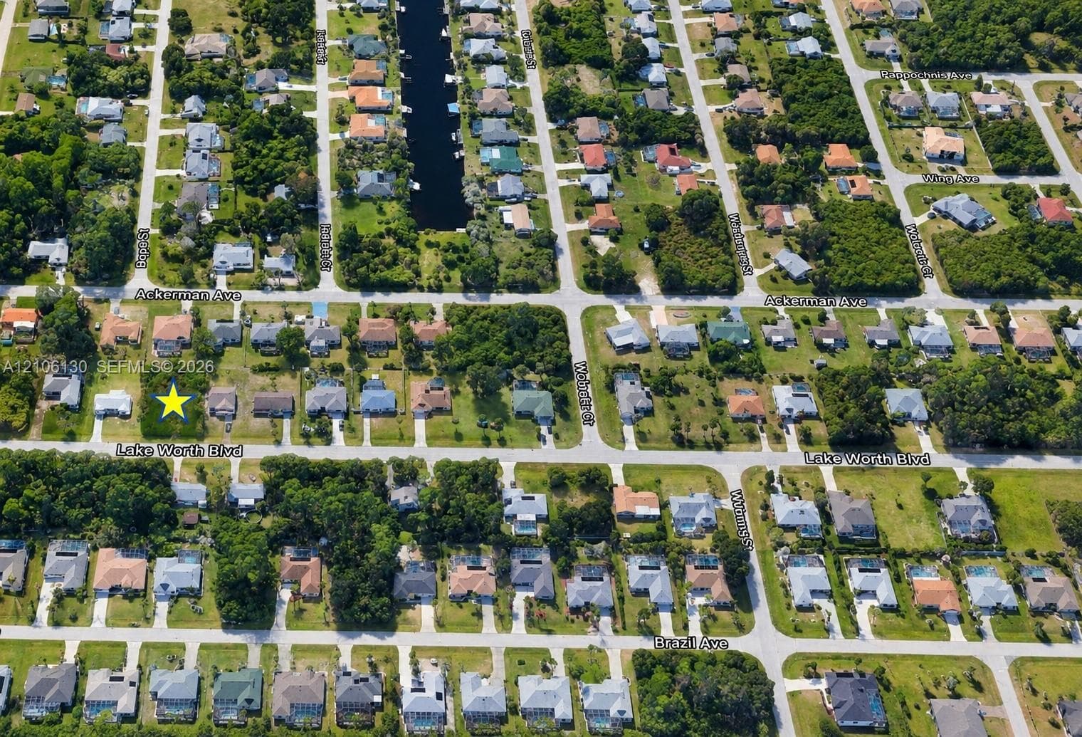 Aerial perspective of a corner lot featuring mature trees, a rectangular parcel footprint, and established residential street infrastructure