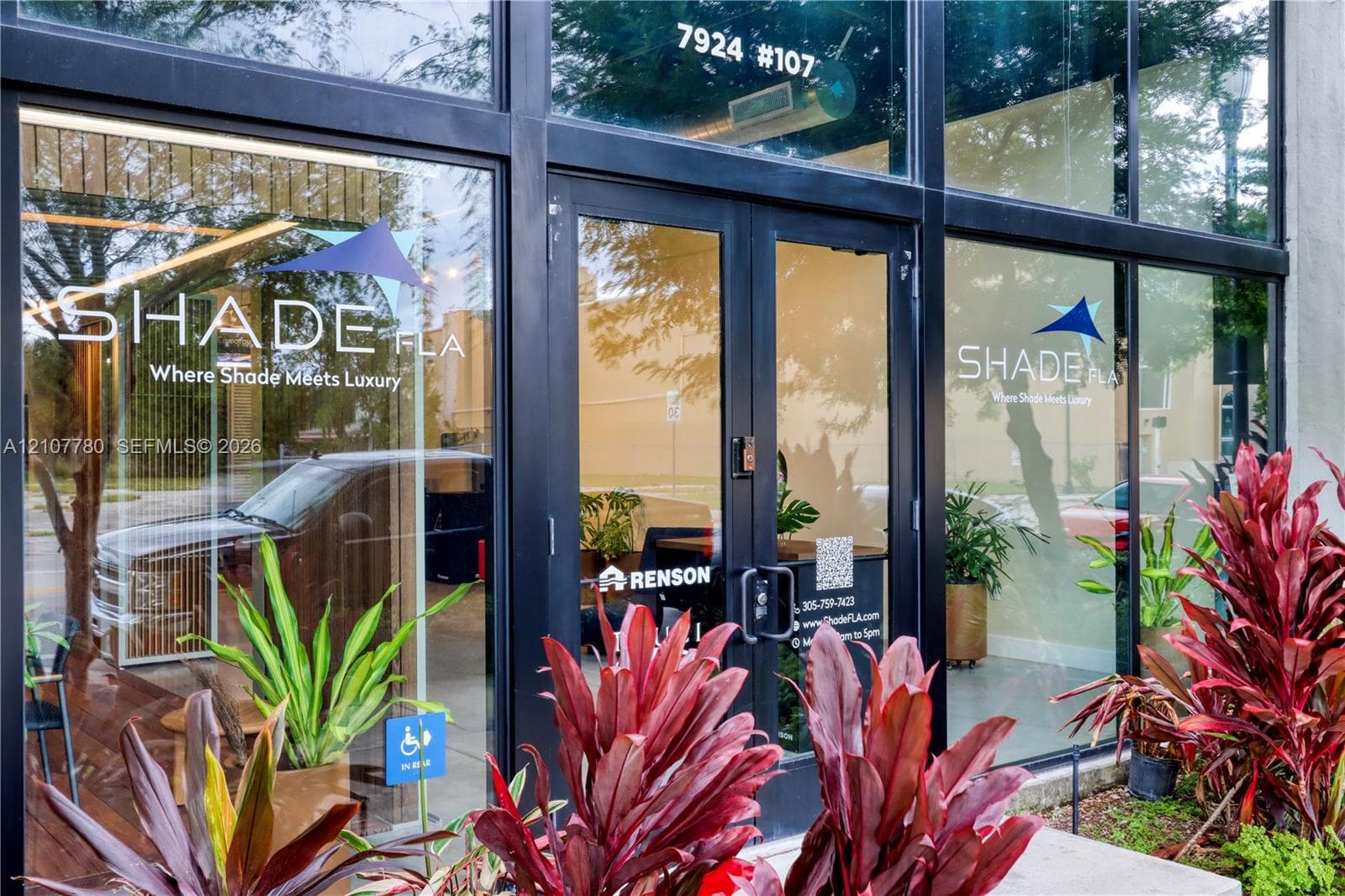 Commercial storefront featuring floor-to-ceiling glass paneling with black metal framing and double glass entry doors