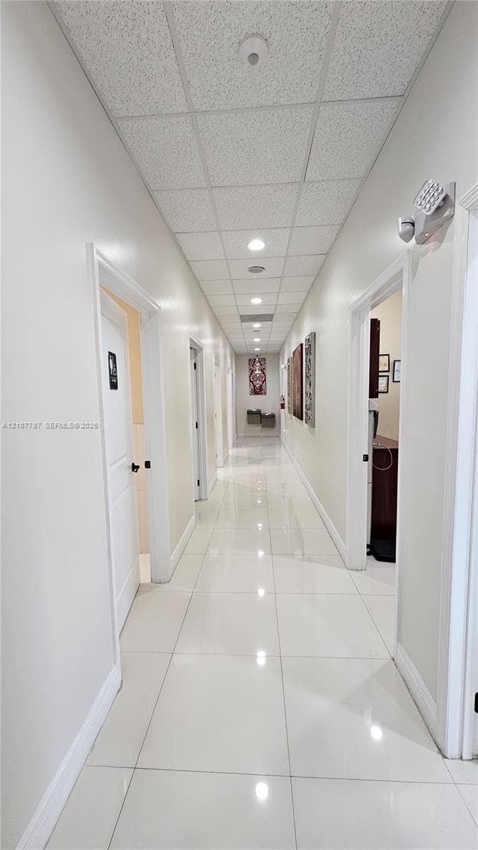 Hallway featuring large-format tile flooring, recessed lighting, and a drop ceiling