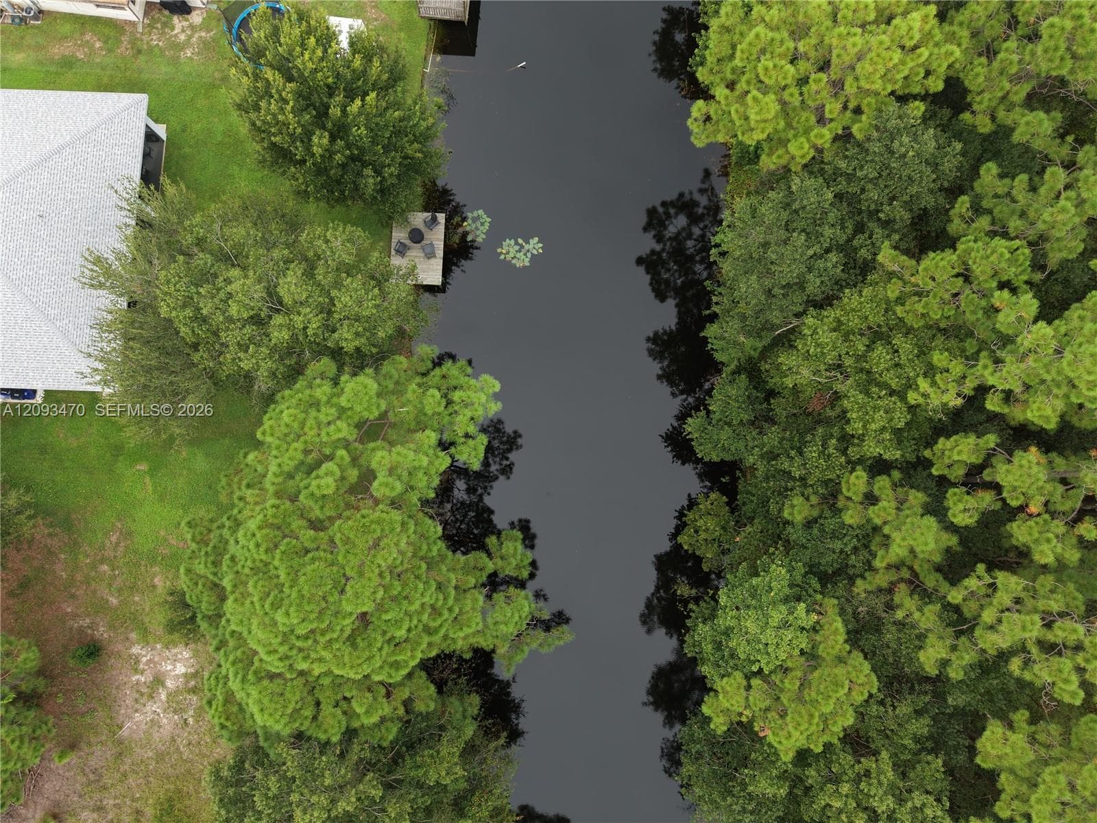Waterfront property featuring a canal, private dock, and mature canopy trees