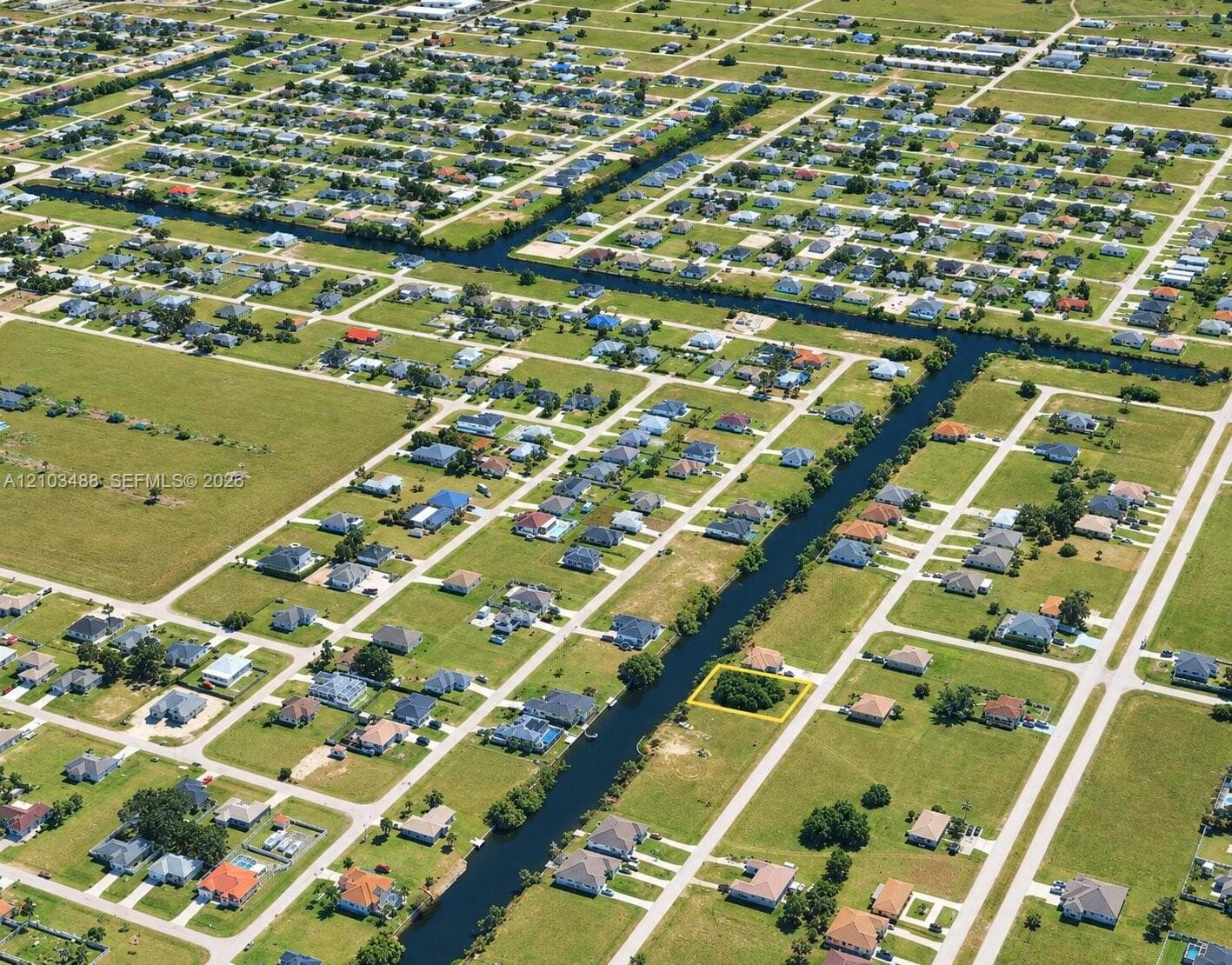 Aerial view of a vacant lot featuring mature trees and canal frontage