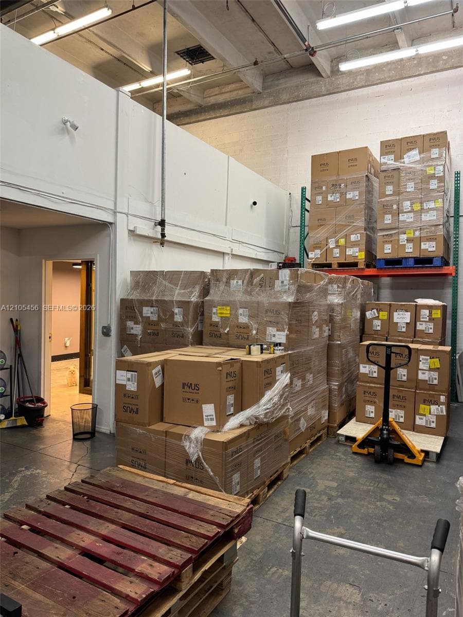 Industrial warehouse space featuring high ceilings with exposed structural beams, reinforced concrete flooring, and built-in metal pallet racking