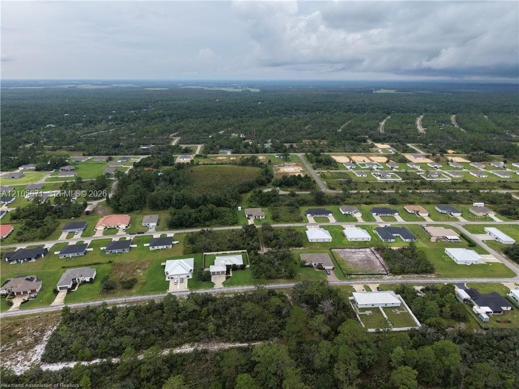 Aerial perspective of a residential neighborhood featuring paved streets, established lot configurations, and surrounding wooded acreage