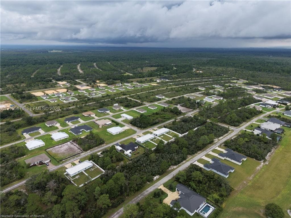 Aerial perspective of a residential development featuring paved street infrastructure, varying lot sizes, and established wooded surroundings