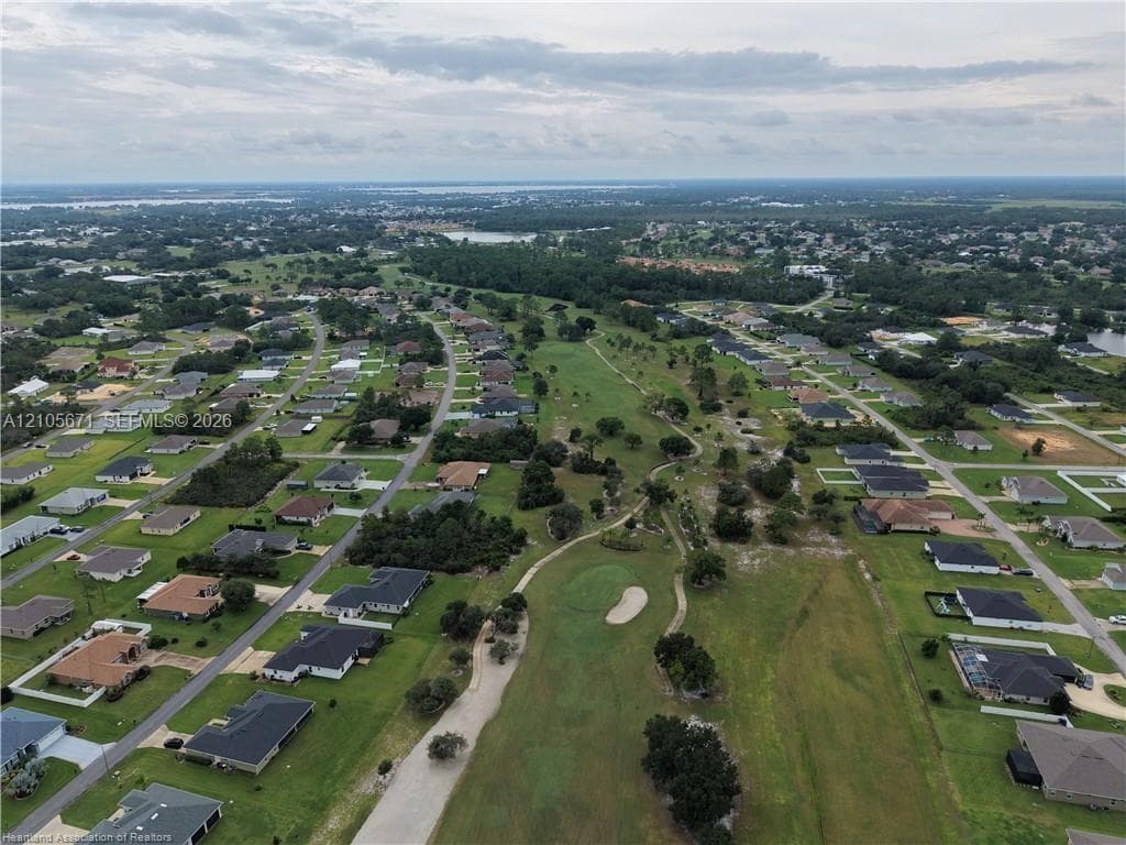 Aerial perspective featuring a manicured golf course fairway, sand bunkers, mature vegetation, and residential lots
