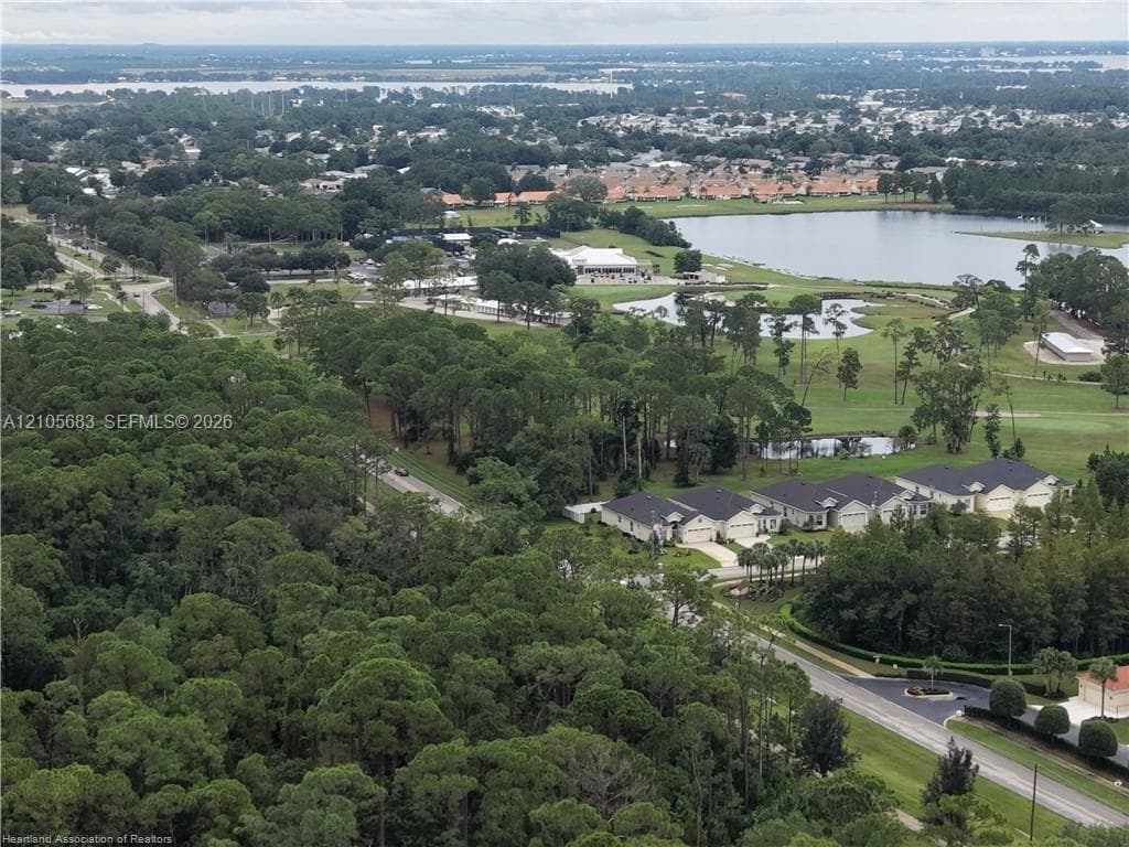 Aerial perspective featuring extensive wooded areas, expansive golf course grounds, natural water bodies, and integrated residential neighborhood clusters