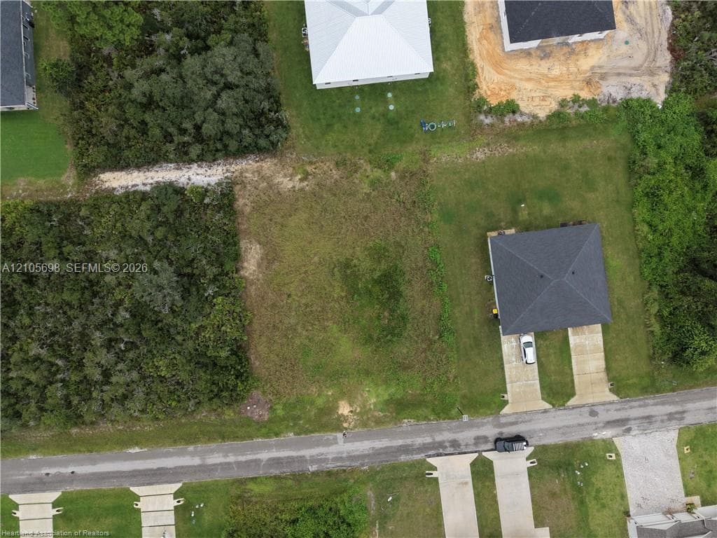Vacant residential lot featuring paved road access, established street frontage, and clearing among mature native vegetation