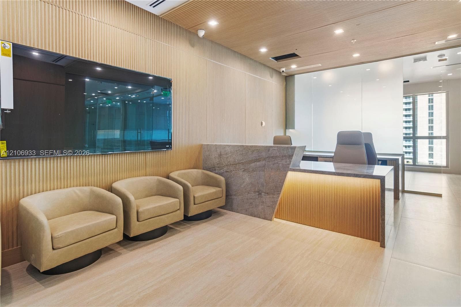 Reception area featuring vertical wood-slat wall paneling, stone-front desk with integrated lighting, wood-finish ceiling, and recessed lighting