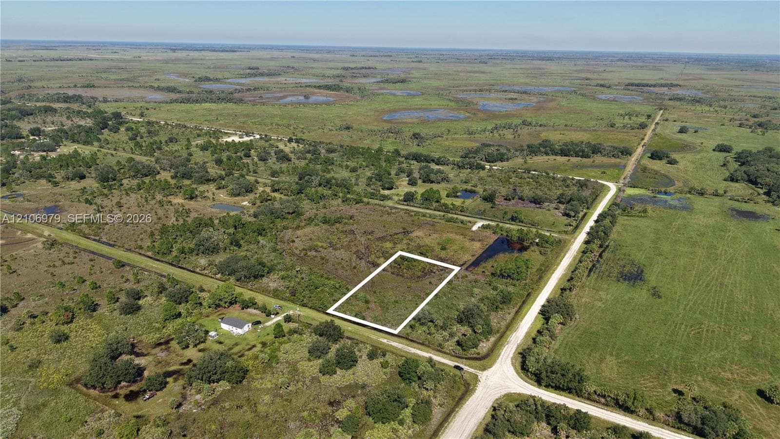 Expansive parcel of land featuring open terrain, mature trees, and direct access to a paved roadway