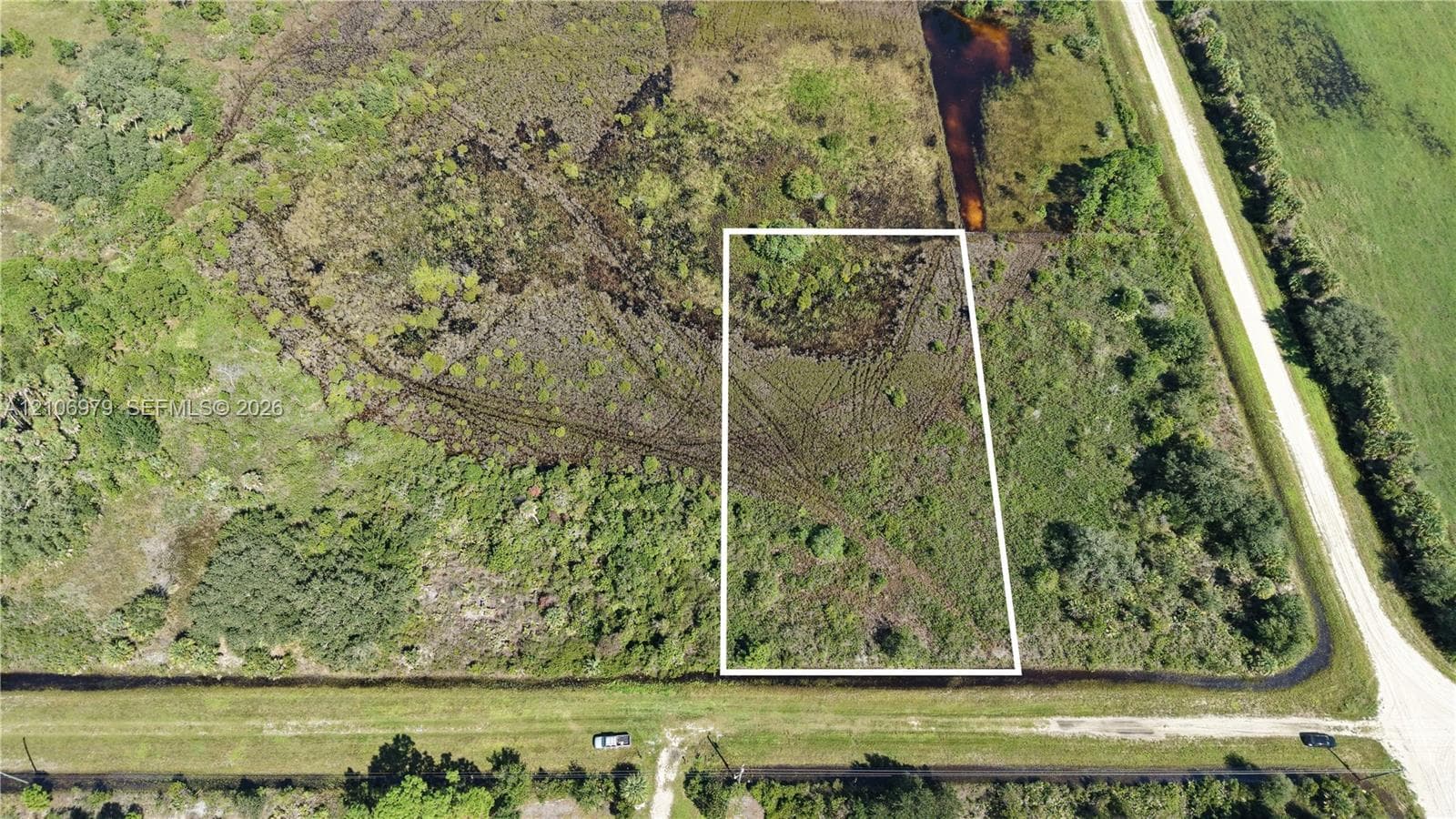 Aerial perspective of undeveloped land featuring native vegetation and direct frontage along a drainage canal