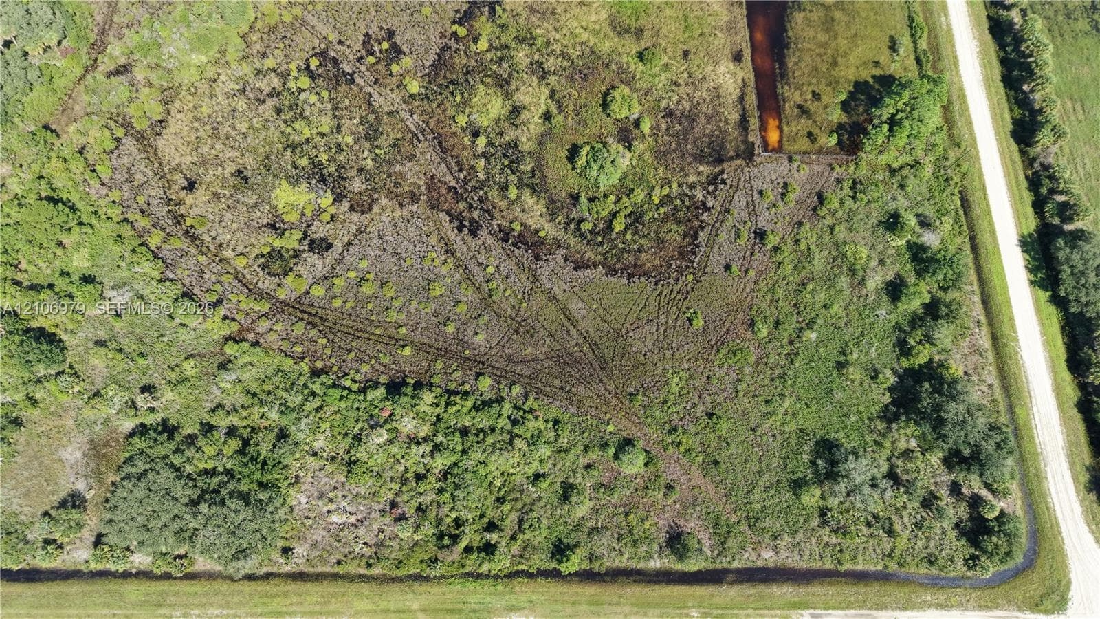 Expansive parcel featuring native vegetation, scattered mature trees, and direct access to an unpaved road