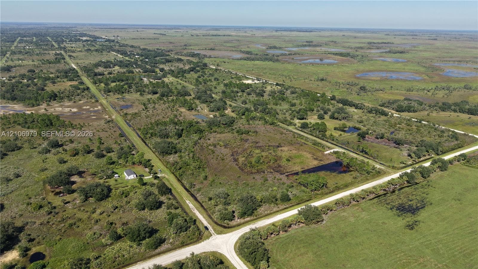 Expansive acreage featuring cleared land, mature trees, natural water features, and frontage on a gravel road