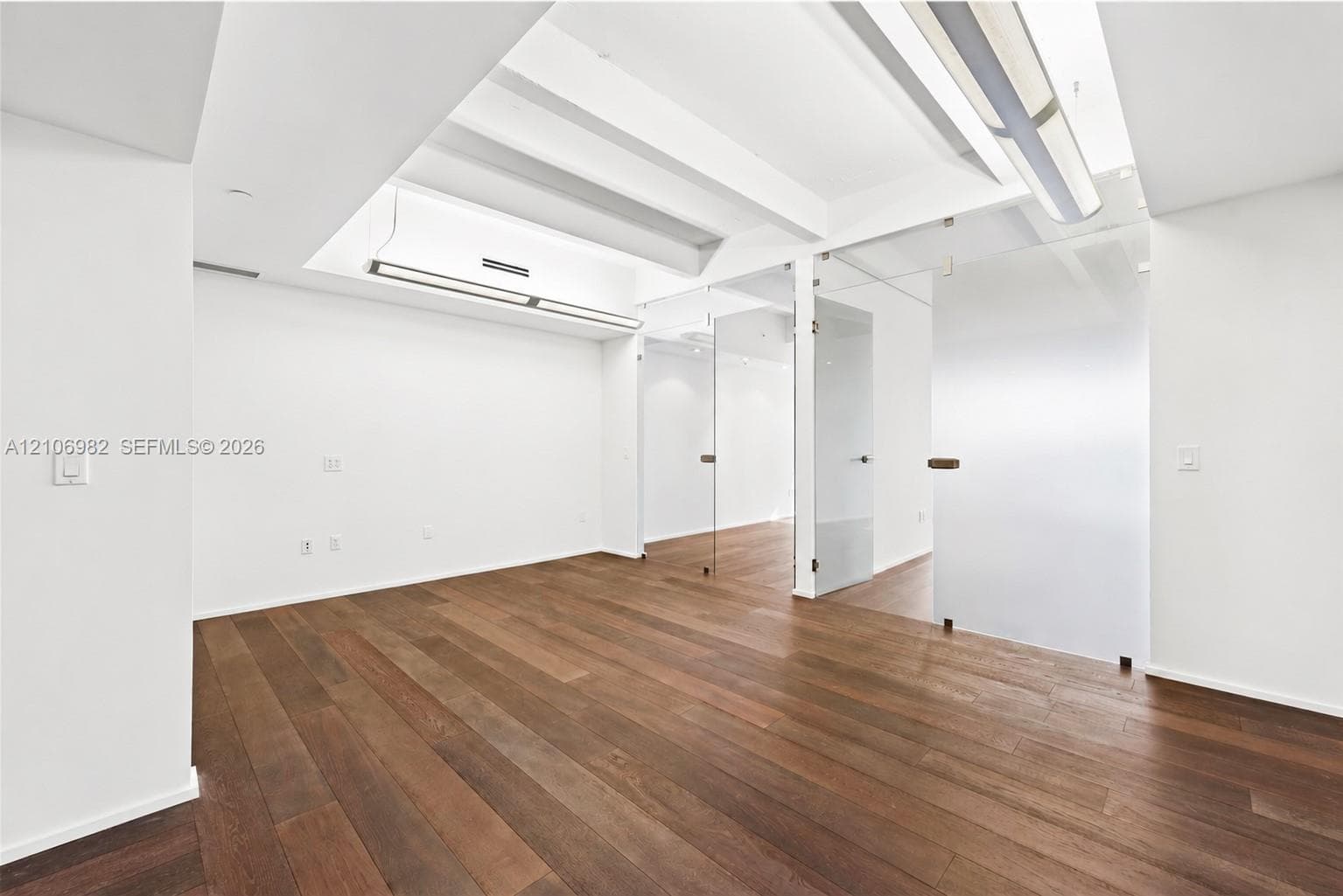 Wood-finish flooring, recessed ceiling lighting, and glass-paneled doors with modern hardware