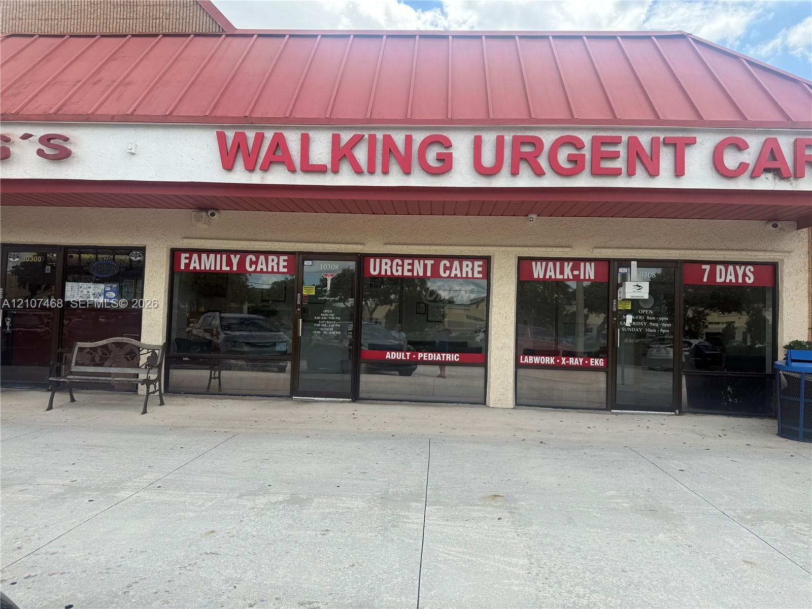 Red metal roof, prominent storefront signage, multiple glass entry doors, concrete walkway, and exterior wall-mounted lighting